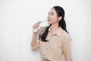 Expression of an Indonesian Asian model woman in white drinking water from a bottle photo