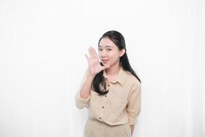 The expression of the Indonesian Asian model woman in white is smiling and making a whispered code or telling photo