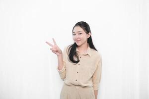 The expression of an Indonesian Asian model woman in white is smiling and making a peace code photo
