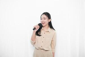 Expression of an Indonesian Asian model woman in white singing using a microphone photo