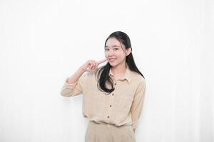 The expression of an Indonesian Asian model woman in white clothes smiling and putting her index finger to her cheek photo