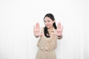 The expression of an Indonesian Asian model woman in white is smiling and making a stop sign photo