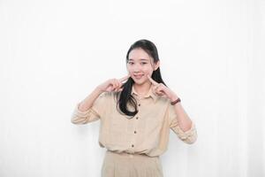 The expression of an Indonesian Asian model woman in white clothes smiling and putting her index finger to her cheek photo