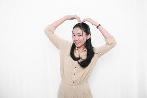 The expression of an Indonesian Asian model woman in white is smiling and making a love code photo