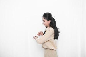 Expression of Indonesian Asian model woman in white dress smiling and looking at watch photo