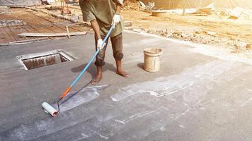 Technician applies concrete curing agent to prevent cracking. concrete primer Steps for applying foundation with a roller on concrete floors Primer for strengthening the surface. photo