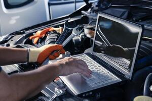 Car inspection service using a modern computer system. and a modern mechanic in the garage Auto mechanics use computer software to check two engines are running and repair them. photo