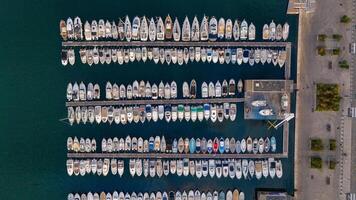 Aerial view of a marina in Marseille, France, with boats and yachts docked in neat rows along the waterfront. The deep blue water contrasts beautifully with the vessels. photo