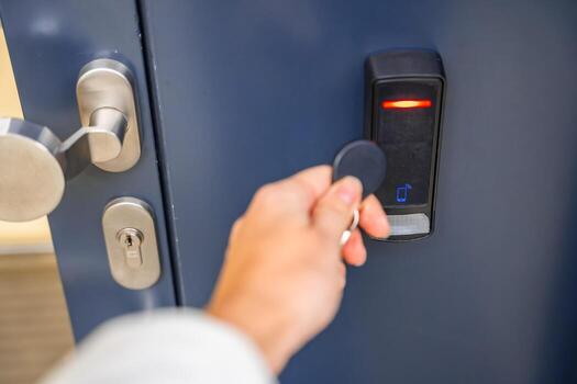 Close up view of person using a electric lock key fob to access a building via a reader of entry system mounted on a house wall. High quality photo