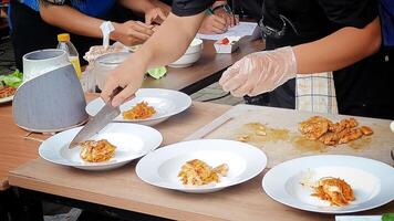 Slicing grilled chicken to serve on a plate with a side dish of vegetables photo