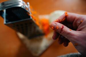A woman cut her finger until it bled on a grater while cooking dinner. photo