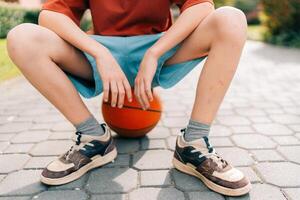 Teen boy tired of playing basketball with ball in summer in the yard photo