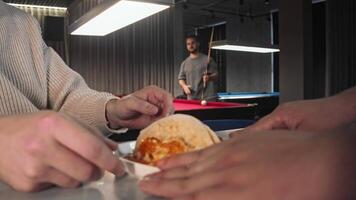 Hungry restaurant guest orders taco with red caviar and fish, which is served on an open plate. There is game of billiards in background video