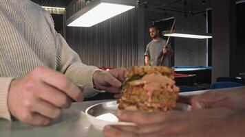 Close-up of the chef's hands as he hands the long-awaited, juicy sandwich with meat and burger sauce to a customer at the billiards club. video