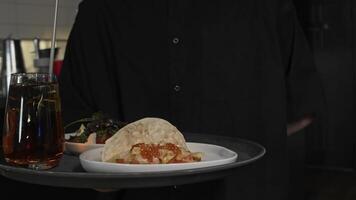 A waiter brings tacos and salads on a tray, along with an alcoholic cocktail, for the diner's enjoyment. Close up. video
