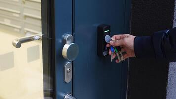 Close up view of person using a electric lock key fob to access a building via a reader of entry system mounted on a house wall. High quality 4k footage video