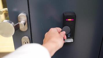 Close up view of person using a electric lock key fob to access a building via a reader of entry system mounted on a house wall. High quality 4k footage video