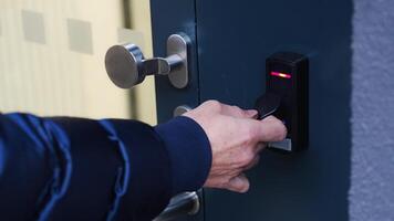 Close up view of person using a electric lock key fob to access a building via a reader of entry system mounted on a house wall. High quality 4k footage video