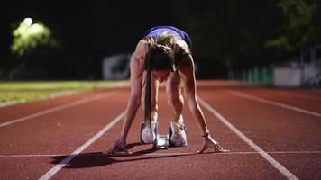 Strong Young Man Starting a Race From Track Starting Blocks Position on a Dark Stadium in the Evening. Cinematic Portrait of a Fit Male Sprint Runner Participating in a Competition video