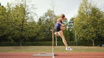 Female Athlete is Running Towards an Obstacle, Hurdling, Jumping Over the Barrier at High Speed while Sprinting in a Race. Cinematic Super Slow Motion video