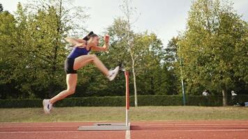 Female Athlete is Running Towards an Obstacle, Hurdling, Jumping Over the Barrier at High Speed while Sprinting in a Race. Cinematic Super Slow Motion video