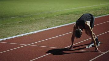 Strong Young Man Starting a Race From Track Starting Blocks Position on a Dark Stadium in the Evening. Cinematic Portrait of a Fit Male Sprint Runner Participating in a Competition video