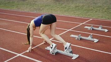 Female Runner on Athletics sprint race starting blocks on a dark background video