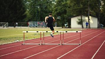 Male Athlete is Running Towards an Obstacle, Hurdling, Jumping Over the Barrier at High Speed while Sprinting in a Race. Cinematic Super Slow Motion video