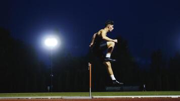 Male Athlete is Running Towards an Obstacle, Hurdling, Jumping Over the Barrier at High Speed while Sprinting in a Race. Cinematic Super Slow Motion video