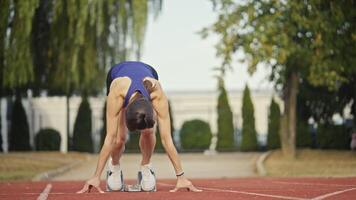 Female Runner on Athletics sprint race starting blocks on a dark background video