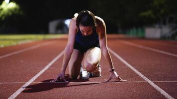 Female Runner on Athletics sprint race starting blocks on a dark background video