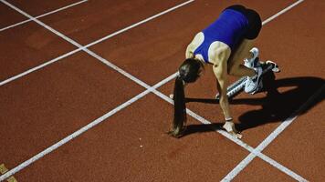 Female Runner on Athletics sprint race starting blocks on a dark background video