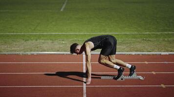 Strong Young Man Starting a Race From Track Starting Blocks Position on a Dark Stadium in the Evening. Cinematic Portrait of a Fit Male Sprint Runner Participating in a Competition video