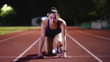 Female Runner on Athletics sprint race starting blocks on a dark background video