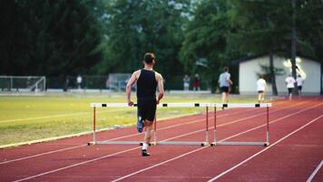 Male Athlete is Running Towards an Obstacle, Hurdling, Jumping Over the Barrier at High Speed while Sprinting in a Race. Cinematic Super Slow Motion video