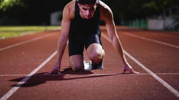 Strong Young Man Starting a Race From Track Starting Blocks Position on a Dark Stadium in the Evening. Cinematic Portrait of a Fit Male Sprint Runner Participating in a Competition video