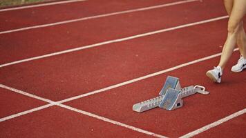 Female Runner on Athletics sprint race starting blocks on a dark background video