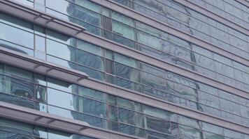A modern office building facade with large glass windows that reflect its surroundings video