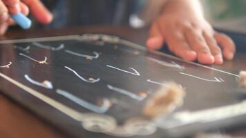 child hand drawing with colorful chalk on a chalkboard on black background video
