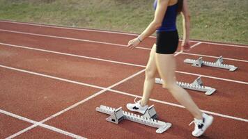 Female Runner on Athletics sprint race starting blocks on a dark background video