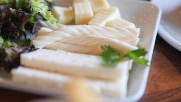 An assortment of delightful cheeses served on a platter with fresh greens for taste video