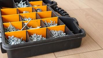 A wood flooring with a toolbox containing screws and drills video