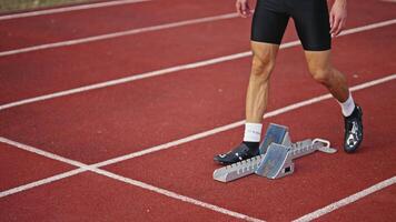Strong Young Man Starting a Race From Track Starting Blocks Position on a Dark Stadium in the Evening. Cinematic Portrait of a Fit Male Sprint Runner Participating in a Competition video