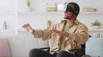 A young man in a wheelchair engages with a virtual reality headset at home, showcasing a moment of immersive technology use in a comfortable setting during the day. video