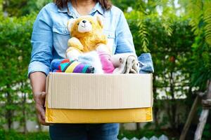 Volunteer collect cloth and doll in cardboard box to donate. photo