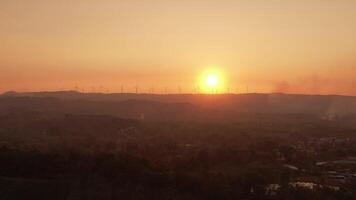 A sunset over a mountain with a wind farm in the background video