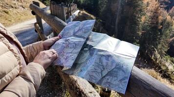 A Caucasian woman holding a map explores a forest trail during autumn, symbolizing adventure and exploration video