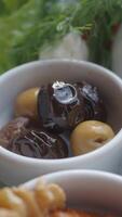 Fresh olives are elegantly displayed in white bowls, arranged with aromatic herbs video