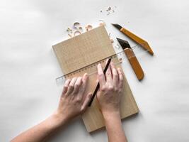 Precision wood carving. hands sketching patterns on wood with knives and ruler photo