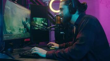 Addicted angry Caucasian guy streamer blogger vlogger influencer man playing online virtual game blog rage losing typing computer speak radio microphone at home player male gamer e-sport scream defeat video